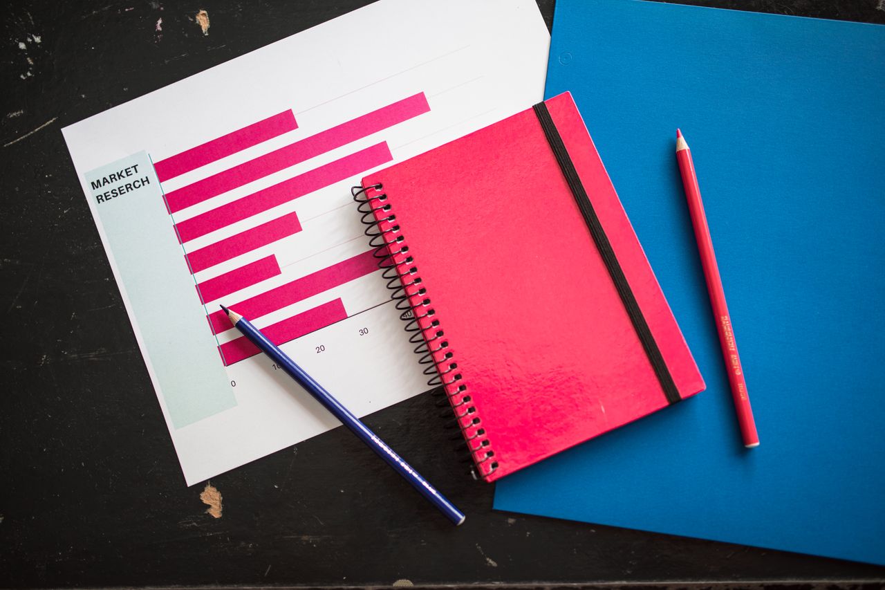 why-choose-us Top-down view of a business chart with a red notebook and colored pencils on the table.